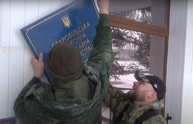 Російські найманці знімають табличку на будівлі державної адміністрації